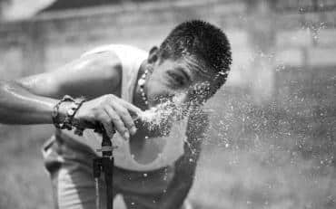 A boy is drinking a water for the water fountain